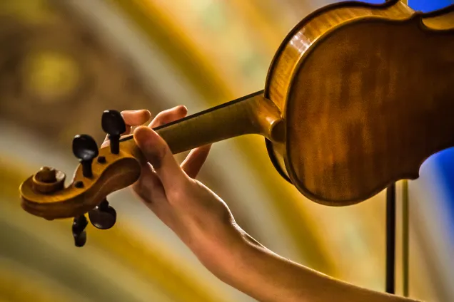 A hand holding a violin. Photo.